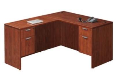 L-shaped brown desk with desk phone sitting on it